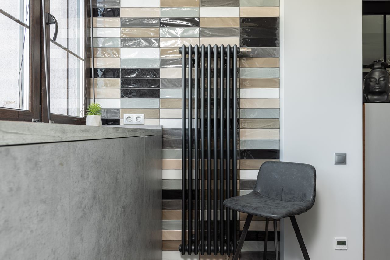 Stylish home interior featuring a tiled wall, radiator, and designer chair.